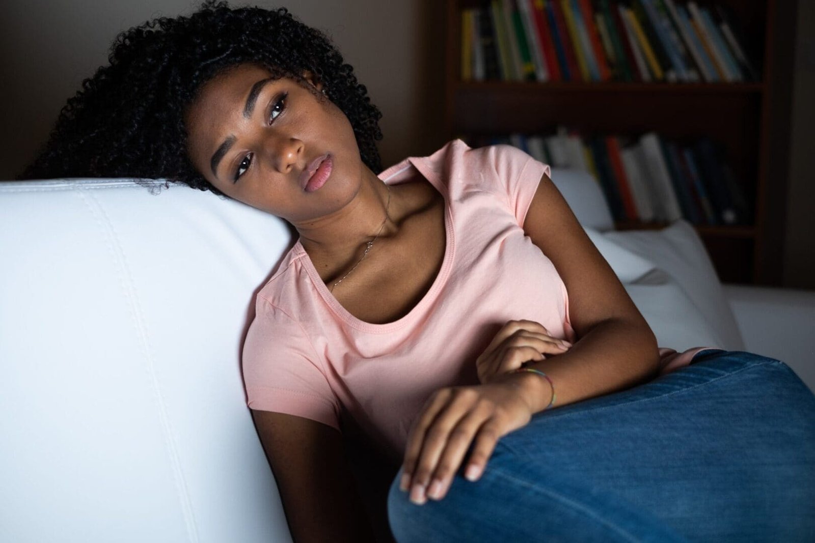 pink shirt | grief counseling in Atlanta, GA | grief specialists in Atlanta, GA | grief and loss counseling in Atlanta | 30213 | 30097 | 30126 Image of a Black woman showing grief symptoms while laying down. Representing someone that is in need of grief and loss counseling in Atlanta, GA. Where a grief specialist can give guidance in grief counseling.