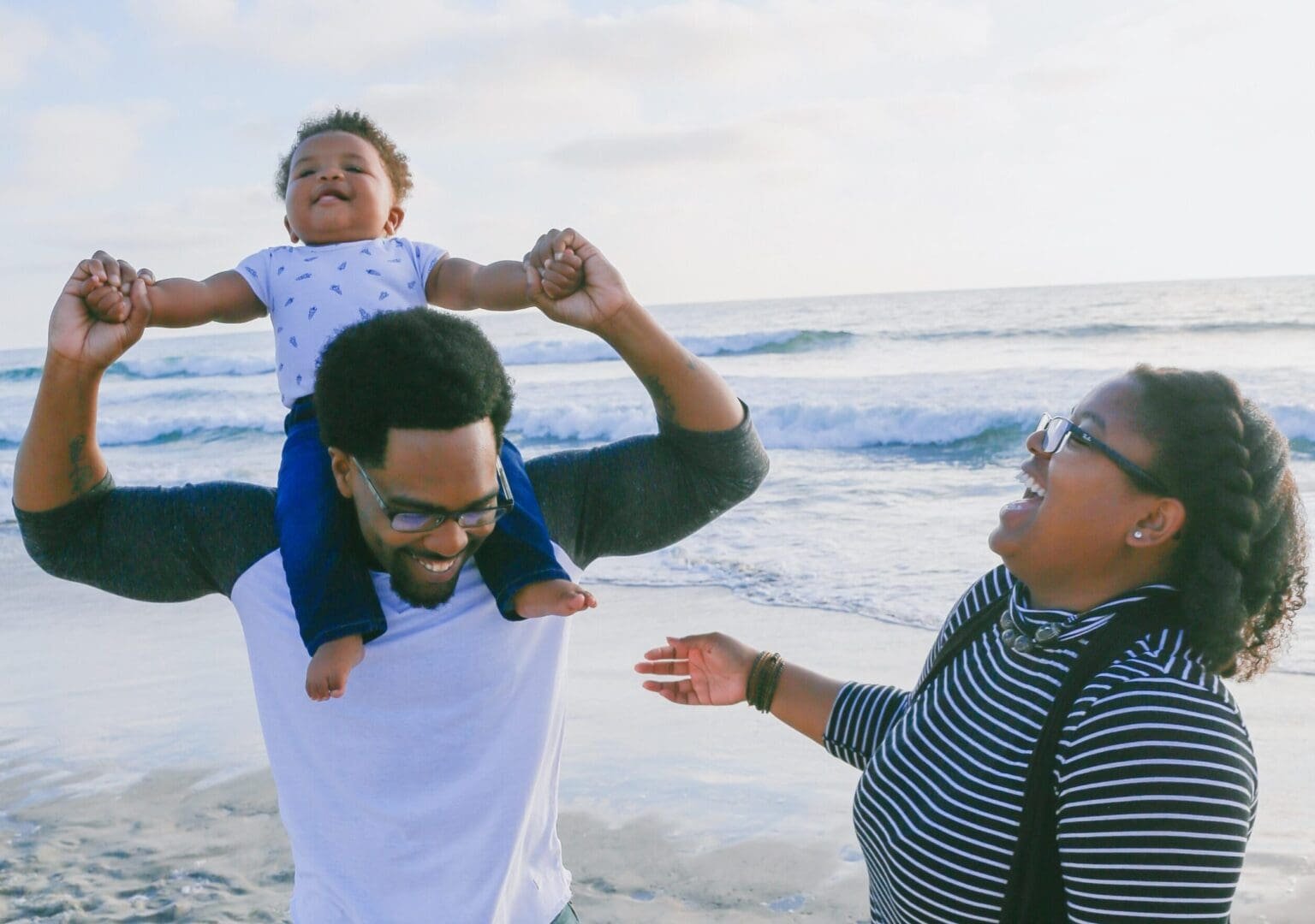 Image of a family of 3 laughing on the beach. Representing freedom that comes after not being controlled by anxiety symptoms in Atlanta, GA. A therapist can help you get there with anxiety therapy.