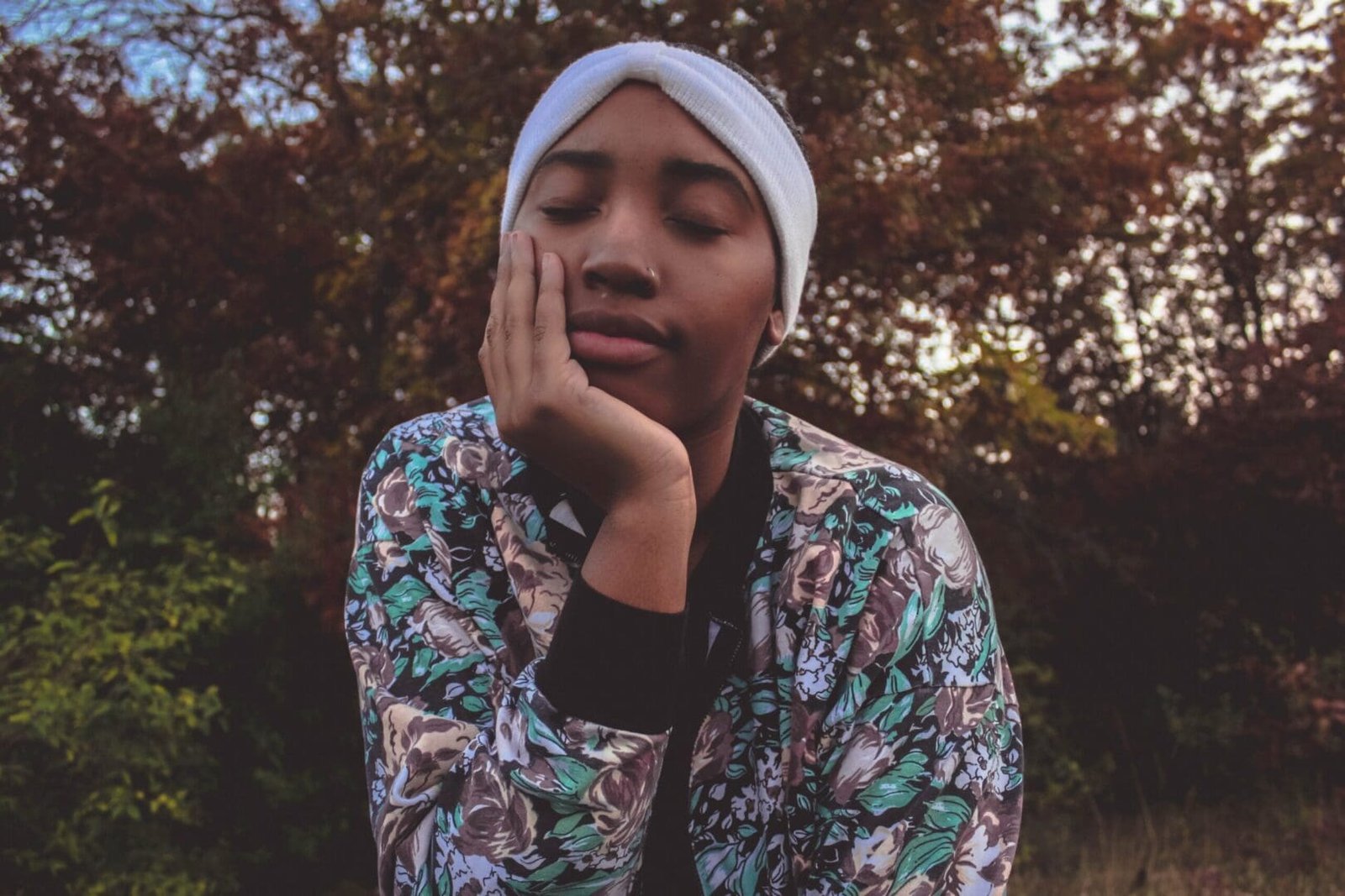 Black woman with eyes closed, taking deep breaths to relax and manage the stress of people-pleasing behaviors